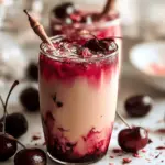 Iced Cherry Earl Grey Milk Tea with fresh cherries and mint in a clear glass on a wooden table.