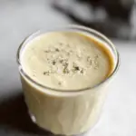 Refreshing pineapple coconut smoothie in a glass with pineapple slice and mint on a tropical beach background.